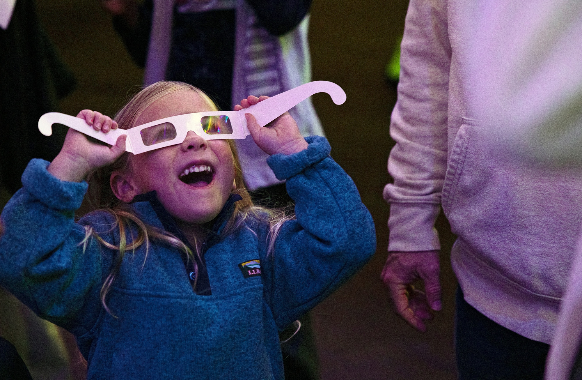 Little girl looking through 3D glasses at holiday lights